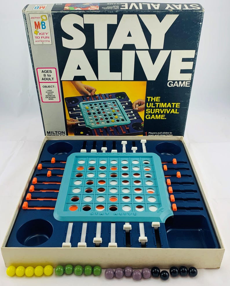 Pode incluir: Um jogo de tabuleiro vintage "Stay Alive". A caixa &eacute; azul escuro com texto branco e uma ilustra&ccedil;&atilde;o do jogo. Dentro, um tabuleiro de jogo turquesa com componentes laranja e brancos fica em uma bandeja azul marinho. Inclui pe&ccedil;as coloridas.