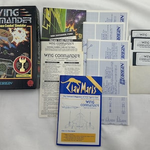 May include: A vintage Wing Commander PC game box set. The box features a space battle scene and the text "Wing Commander: The 3-D Space Combat Simulator." Includes game disks, manuals, and a magazine.