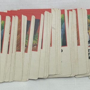 May include: A deck of vintage game cards with red borders and illustrations. One card reads "MOVE ANY OPPONENT BACK 3 SPACES." The cards feature various images and text, suggesting a board game or card game.