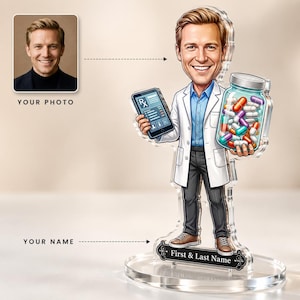 Könnte beinhalten: Ein personalisierter Acryl-Aufsteller mit einer Comic-Figur eines medizinischen Fachpersonals in weißem Kittel, blauem Hemd und dunkler Hose. Die Figur hält ein Tablet mit Rx-Symbol und ein Glas mit bunten Kapseln auf einem runden Sockel.