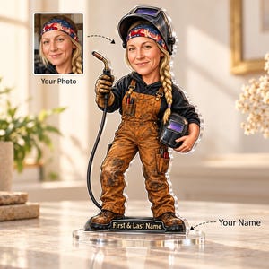 May include: A custom bobblehead figurine of a welder wearing brown work overalls, a black hoodie, and a patterned headband. The figure holds a welding torch and a helmet, standing on a clear base with a plaque labelled First & Last Name.