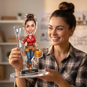 Può includere: Una figura in acrilico trasparente di una donna lavoratrice edile che tiene in mano dei progetti e una cassetta degli attrezzi. La figura indossa una camicia rossa, jeans blu e stivali da lavoro. La base ha il testo "First & Last Name".