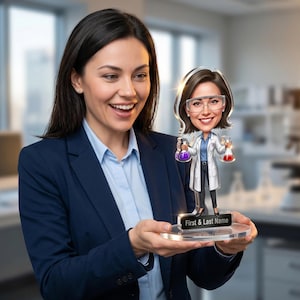 Pode incluir: Uma mulher de blazer azul e camisa azul clara segura uma caricatura personalizada em acrílico de uma cientista. A caricatura apresenta uma cientista de desenho animado em um jaleco de laboratório, segurando béqueres com líquidos roxos e vermelhos. A base da caricatura diz "First & Last Name".