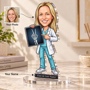 Peut inclure: Une figurine en acrylique personnalisée représentant un professionnel de santé en style dessin animé, aux cheveux blonds, portant une blouse blanche et une tenue médicale bleu sarcelle, tenant une radiographie d'une main faisant un signe V.