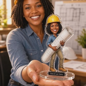 Peut inclure: Un présentoir en acrylique transparent représentant une illustration de dessin animé d'un professionnel de la construction portant un casque jaune, une chemise bleue et un pantalon beige, tenant un grand plan roulé. La base inclut une plaque noire avec le texte First & Last Name.