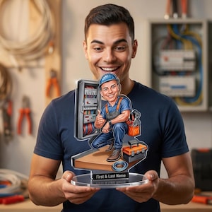 Puede incluir: Una persona sosteniendo una placa acrílica personalizada con un electricista de dibujos animados. El electricista de dibujos animados lleva un uniforme azul y un casco, dando un pulgar hacia arriba. La placa tiene espacio para un nombre.