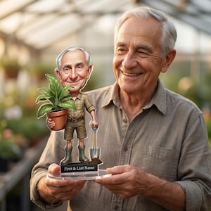 May include: An elderly man smiles, holding a caricature of himself in a greenhouse. The caricature shows a man with a plant in a pot, a shovel, and the text "First & Last Name" on the base, all on a clear stand.