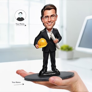May include: A custom bobblehead figurine of a person wearing a black suit, white shirt, and glasses. The figure holds a yellow hard hat in one hand and a rolled blueprint in the other, standing on a black oval base with the text First & Last Name.
