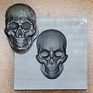 May include: A black skull mold with a detailed design. The mold is made of a smooth, dark material and has a realistic skull shape.