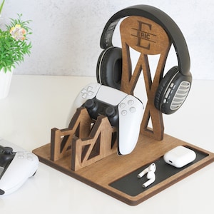 Peut inclure: Support en bois avec un porte-casque, deux emplacements pour les manettes et un petit compartiment pour les écouteurs. Le support est personnalisé avec le nom "Eric".