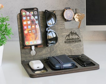 May include: A wooden organizer with compartments for a phone, sunglasses, a watch, keys, a wallet, and other small items. The organizer has a mountain design and the name "ROBINSON" engraved on it.