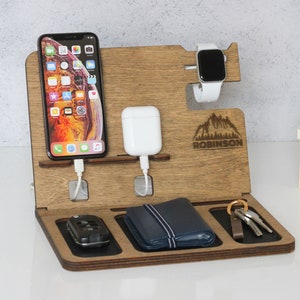 May include: Wooden phone charging station with a phone, watch, wireless charger, keys, and a wallet. The station is personalised with the name "ROBINSON" and a mountain design.