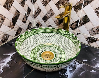 May include: A green and white ceramic sink with a decorative pattern. The sink has a round shape and a drain in the center. The sink is set against a background of black and white tiles.