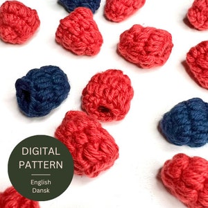 Pode incluir: Um padrão digital para crochetar framboesas e mirtilos. O padrão está disponível em inglês e dinamarquês.