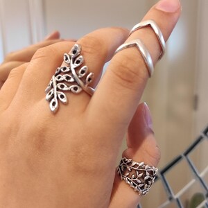 May include: Three silver rings, one with a leafy design and two with a chevron pattern.