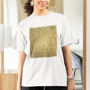 May include: White t-shirt with a gold print of Korean text. The text is in a traditional style and appears to be a poem or a story.