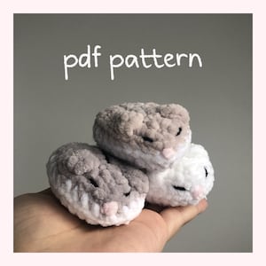 Puede incluir: Tres peluches de hámster de crochet en gris, blanco y una combinación de gris y blanco. Los peluches están apilados uno encima del otro y se sostienen en la mano de una persona. El texto "pdf pattern" está escrito en blanco sobre un fondo gris encima de los peluches.