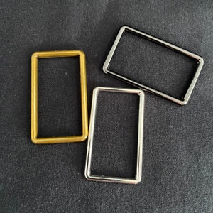Könnte beinhalten: Drei rechteckige Metallrahmen in Gold, Silber und Schwarz.