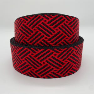Könnte beinhalten: Zwei Rollen schwarzes und rotes elastisches Band mit Muster. Das Muster ist ein geometrisches Chevron-Design.
