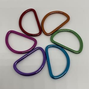 Könnte beinhalten: Sechs D-Ringe aus Metall in einem Regenbogen aus Farben: Rot, Orange, Grün, Blau, Lila und Pink. Die Ringe sind in einem Kreis angeordnet.