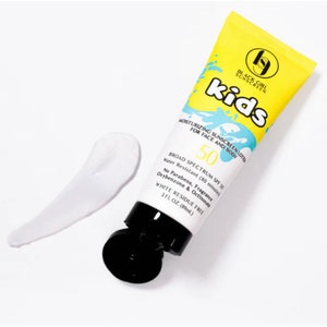 Op de afbeelding: Een gele tube Black Girl Sunscreen Kids hydraterende zonnebrandcrème met een witte crèmevlek. De tube heeft blauwe en witte tekst met de tekst "kids" en "50 SPF". Het product is waterbestendig en laat geen witte resten achter.