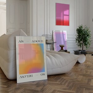 Könnte beinhalten: Ein weißes Sofa mit einem gerahmten Poster, das einen Farbverlauf von Rosa, Orange und Gelb zeigt. Das Poster hat den Text "AS - ABOVE - SO - BELOW" darauf gedruckt. Das Poster lehnt an der Couch.
