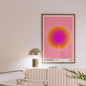 May include: A framed print with a pink background and a large, gradient circle in the center. The circle transitions from yellow to orange to pink. The text "SUPPORT" is printed below the circle, along with a small number.