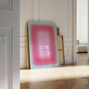 May include: A framed abstract painting with a gradient of pink, red, and blue colours. The painting is leaning against a white wall.