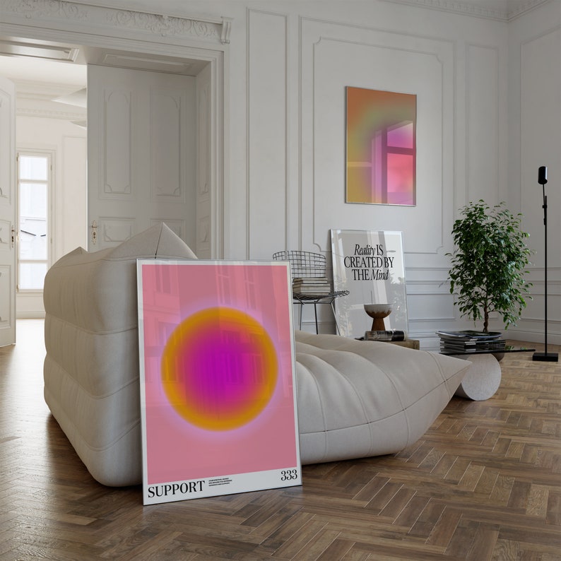 May include: A pink and orange abstract art print with a circle in the center. The print has the text "SUPPORT" and "333" at the bottom. The print is hanging on a white wall in a living room.