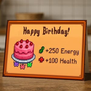 Könnte beinhalten: Eine Geburtstagskarte mit Pixel-Design. Die Karte zeigt einen rosa Kuchen mit roten Kirschen, die Worte "Happy Birthday!" und spielartige Gesundheits- und Energie-Boni. Die Karte befindet sich vor einem verschwommenen Küchenhintergrund.