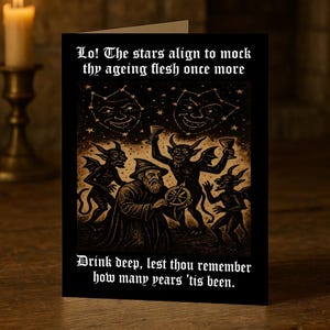 Può includere: Biglietto di auguri nero con testo gotico e illustrazioni. La carta presenta un mago, demoni e immagini celesti. Il testo recita: "Lo! Le stelle si allineano per deridere la tua carne invecchiata ancora una volta. Bevi a fondo, per non ricordare quanti anni sono trascorsi."