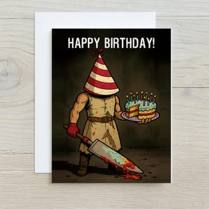 May include: Greeting card featuring a cartoon illustration of a figure in a party hat, holding a bloody cleaver and a birthday cake. The text "HAPPY BIRTHDAY!" is at the top. The card is set against a white background.