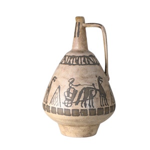 Puede incluir: Una jarra de cerámica con un diseño marrón y blanco. La jarra tiene una base ancha y un cuello estrecho con una asa. El diseño presenta una escena de un carro tirado por dos caballos, con una figura en el carro. La jarra está decorada con patrones geométricos.