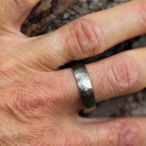 men's wedding ring band in the alternative metal of titanium. This ring has a hammered finish and polished inside the ring is 6 millimetres wide and comes in a recycled material ring box