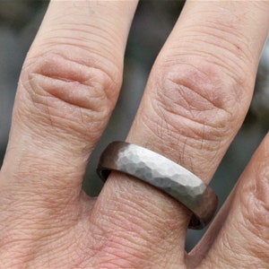 men's wedding ring band in the alternative metal of titanium. This ring has a hammered finish and polished inside the ring is 6 millimetres wide and comes in a recycled material ring box