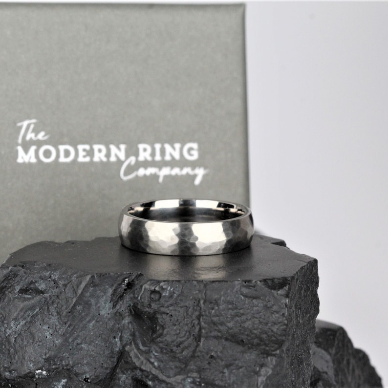 mens wedding ring band in the alternative metal of titanium. This ring has a hammered finish and polished inside the ring is 6 millimetres wide and comes in a recycled material ring box