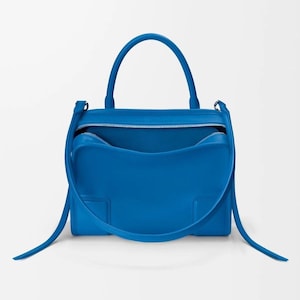 Pode incluir: Uma mala azul brilhante com uma al&ccedil;a superior e uma al&ccedil;a de ombro remov&iacute;vel. A mala tem formato retangular com abertura superior com z&iacute;per. O interior &eacute; azul combinando. A mala &eacute; feita de material liso.
