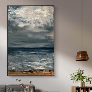 Puede incluir: Pintura al óleo abstracta de un paisaje marino con un cielo oscuro y tormentoso y un océano. La obra de arte presenta pinceladas texturizadas en tonos de azul, gris y blanco, con una línea costera marrón. La pintura está enmarcada en un marco de madera negro.