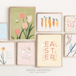 Może przedstawiać: Kolekcja ośmiu oprawionych wydruków z motywami wielkanocnymi. Wydruki przedstawiają ilustracje tulipanów, marchewek, królików, kurcząt, ptaka i jajek. Wydruki są w różnych kolorach, w tym różowym, zielonym, żółtym i niebieskim. Wydruki są ułożone w siatkę na białej ścianie.