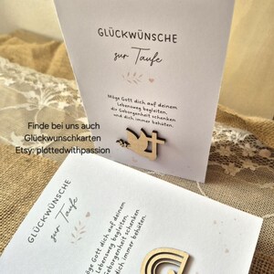 May include: Two white greeting cards for a baptism, each featuring German text and a wooden cutout. One card displays a dove and cross, while the other features a rainbow with a heart. The cards include the printed text GL&Uuml;CKW&Uuml;NSCHE zur Taufe.