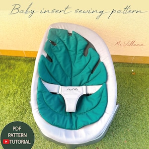 Könnte beinhalten: Ein Schnittmuster für einen Babyeinsatz mit einem teal-farbenen, blattförmigen Kissen in einer grauen Babywippe. Die Wippe hat einen weißen Sicherheitsgurt mit dem Markennamen "nuna". Der Text "Baby insert sewing pattern" ist zu sehen.