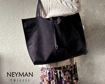 May include: A large, dark purple tote bag with long straps and a drawstring closure. The bag has a simple design and a small tag. The text "NEYMAN TBILISI" is visible in the lower left corner.