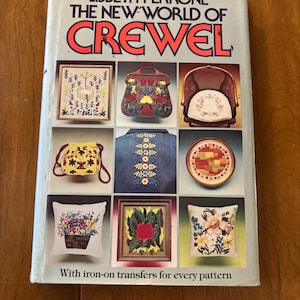 May include: A book titled "The New World of Crewels" by Lisbeth Perrone. The cover features colorful crewel embroidery designs on various items, including a chair, a purse, a pillow, and a jacket. The book includes iron-on transfers for each pattern.