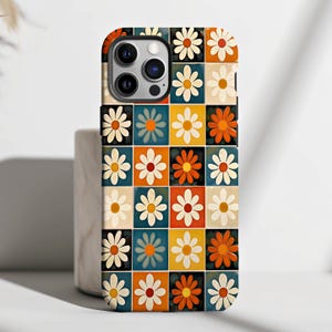 May include: A phone case featuring a retro-style pattern of colourful daisies on a white background. The case is designed for an iPhone 14 Pro Max.