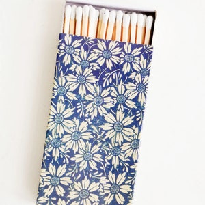 May include: A box of matches with a blue and white floral design. The matches have white tips and are arranged in rows.