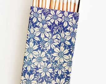 May include: A box of matches with a blue and white floral design. The matches have white tips and are arranged in rows.