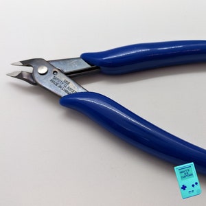 May include: Blue handled wire cutters with a silver blade. The blade has the text "USE SAFETY GLASSES MADE IN CHINA" on it.