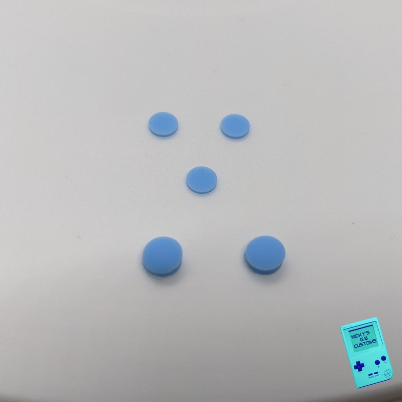 Peut inclure: Cinq boutons ronds bleu clair sur une surface blanche.