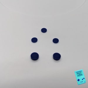 Peut inclure: Cinq boutons ronds bleu fonc&eacute; dispos&eacute;s en forme de triangle sur une surface blanche.