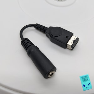 May include: A black audio cable with a 3.5mm jack on one end and a GameCube controller port on the other end.